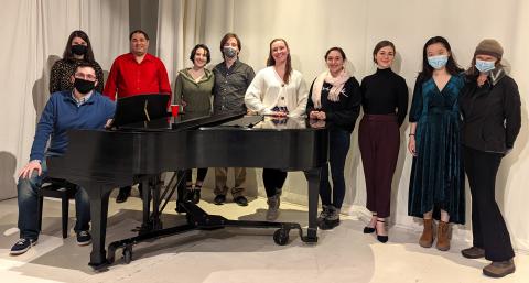 Friendly singers gather around the piano to celebrate a successful studio class